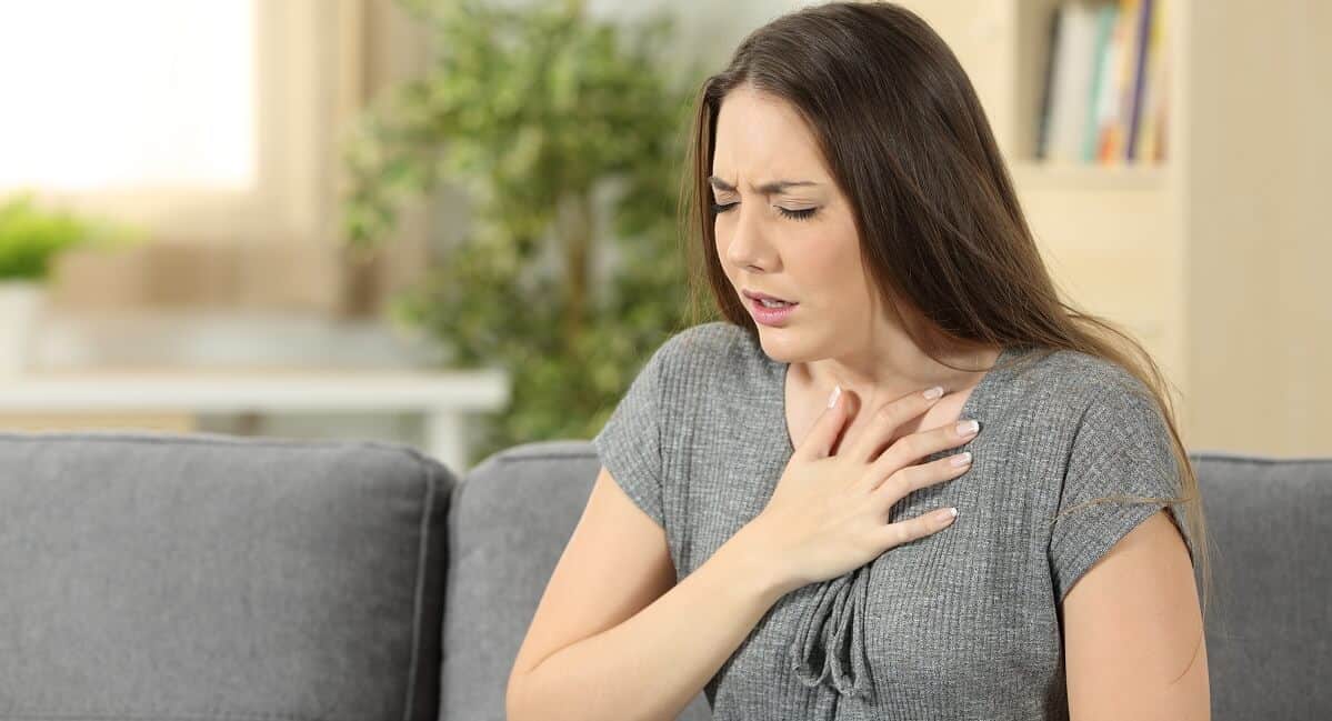 woman suffering respiration problems sitting on a couch in the living room at home