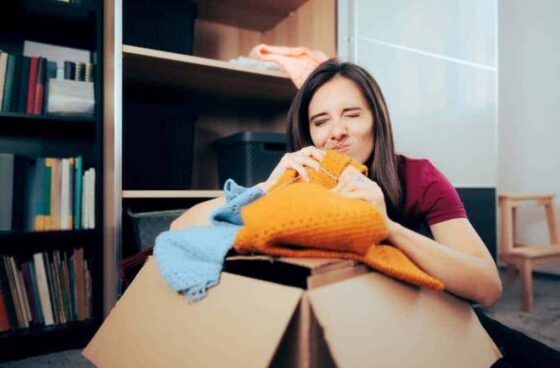 Woman smelling clothes in a moving box